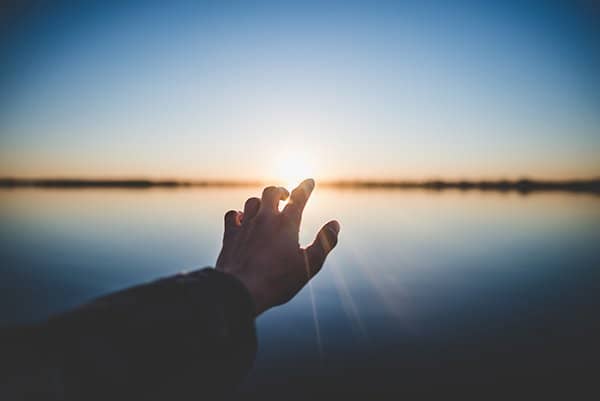 pursue virtue | hand reaching out to sunset